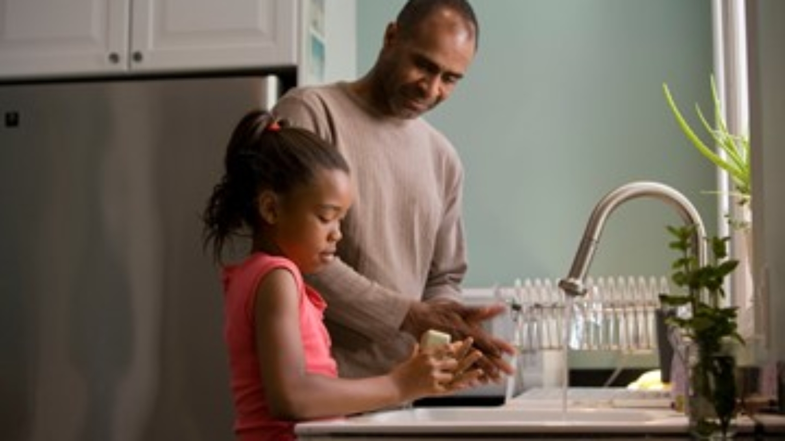 A father and daughter washing dishes together.