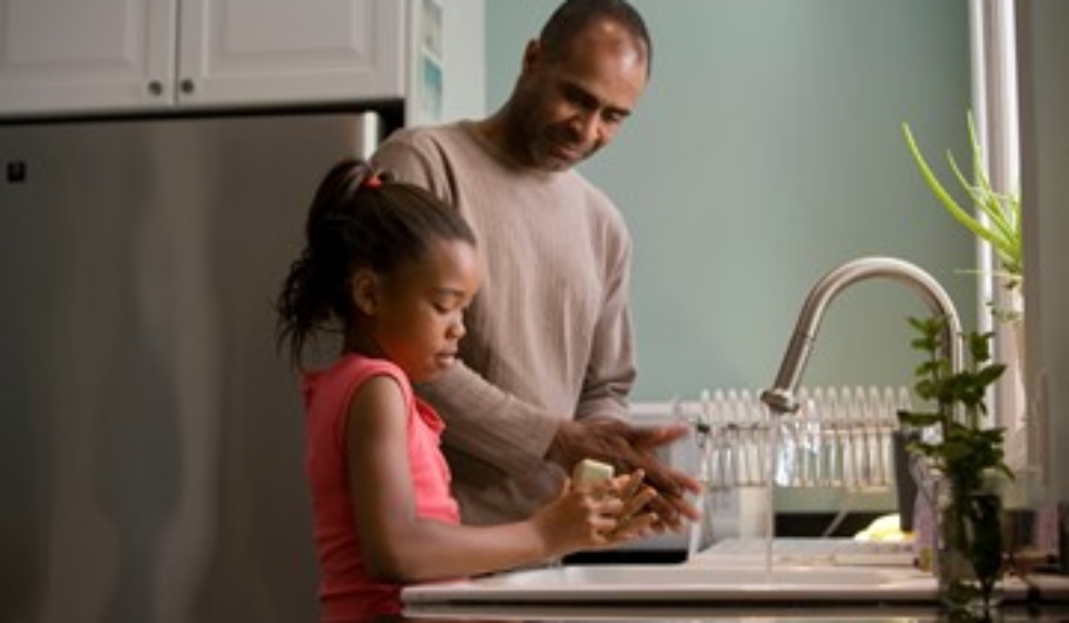 A father and daughter washing dishes together.